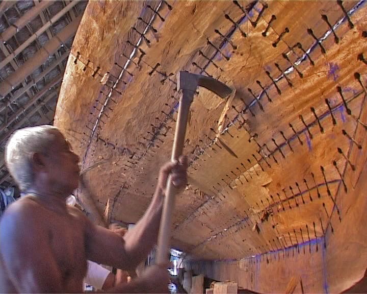 Master boatwright shaping the wooden ribs of a traditional Lakshadweep vessel with an adze