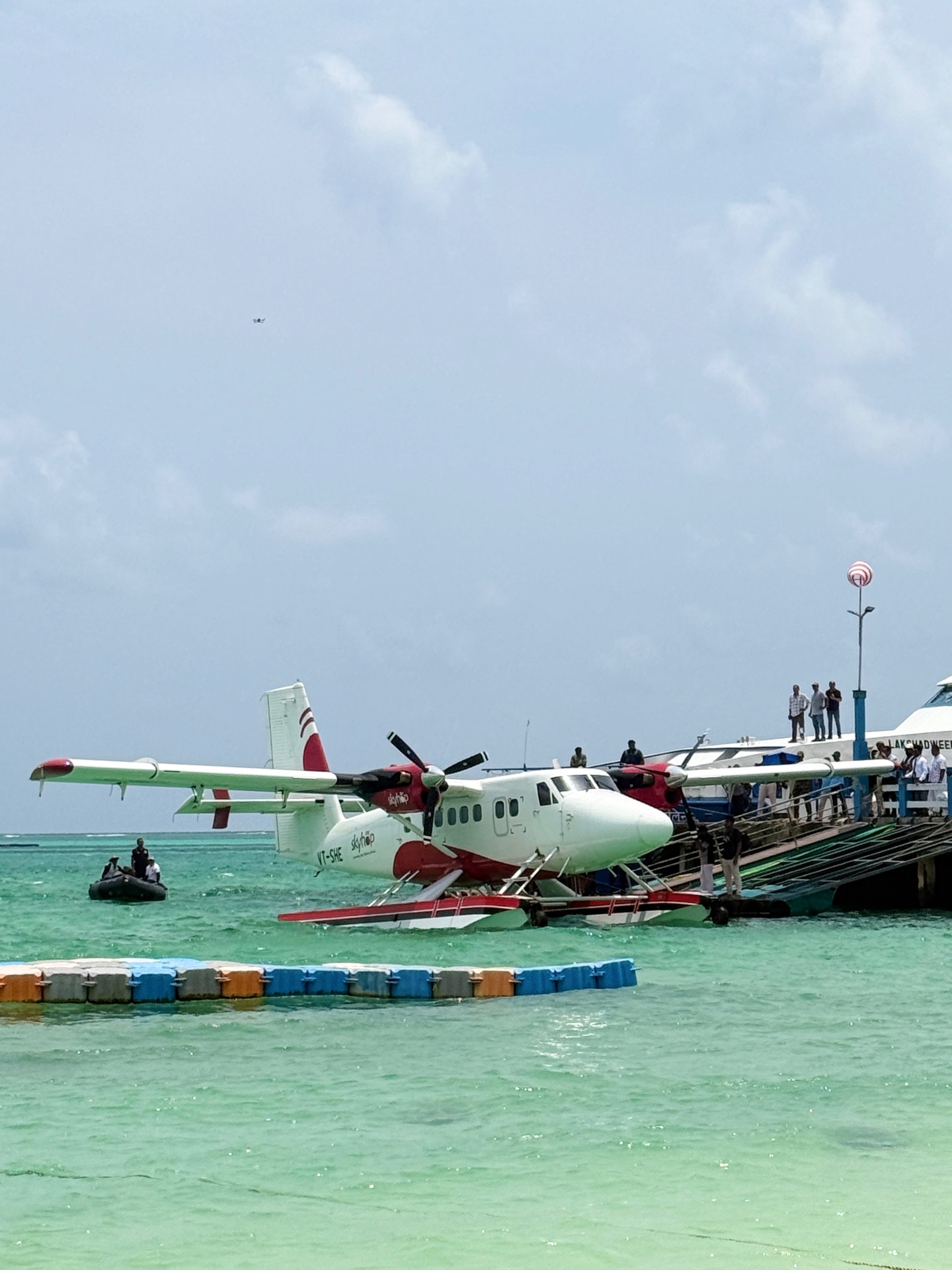 Twin Otter seaplane docked at a Lakshadweep jetty with turquoise lagoon water around its floats