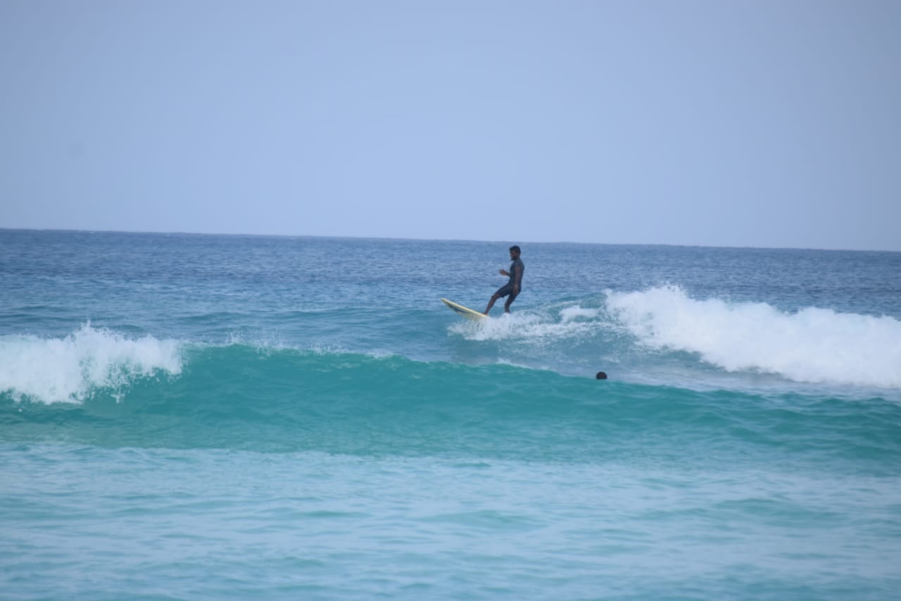 Surfer paddling out in the turquoise lagoon of Lakshadweep